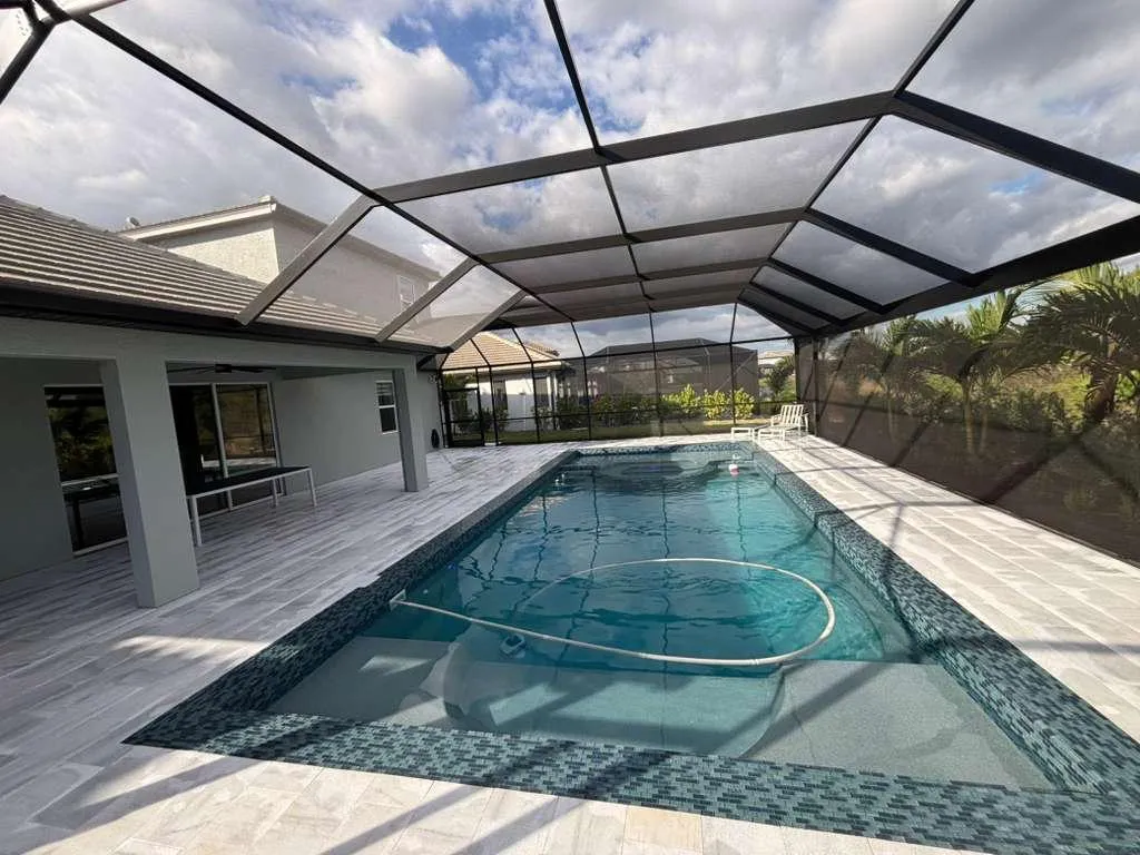 Custom pool cage enclosure with screen mesh protecting pool area from bugs